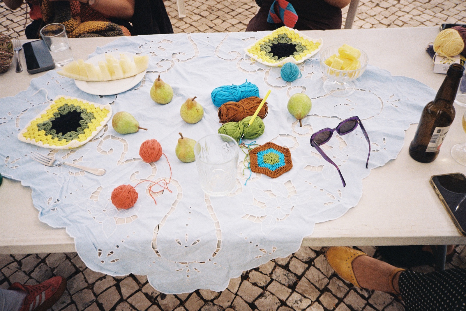 Yarn, crochet motifs, hooks and pears arranged on a shared table